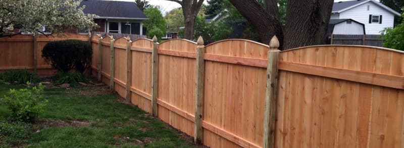 Wood privacy fence with arched top along a yard