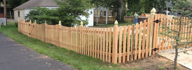 Wood picket fence with pointed posts along a lawn