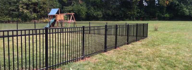 Black aluminum fence around a yard with playset